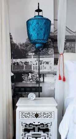 中式传统镂空花纹设计的白色床头柜，配以蓝色灯笼式的床头灯，营造出充满风韵的柔软中国风