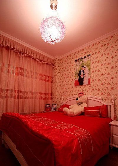 欧式田园风格的白色双人床搭配中国红的软装配饰，使得婚房温馨浪漫，富有中国古典风情