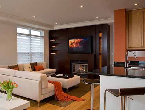 米白色的沙发上摆放橙色的靠垫，给这个客厅增加了一点色彩